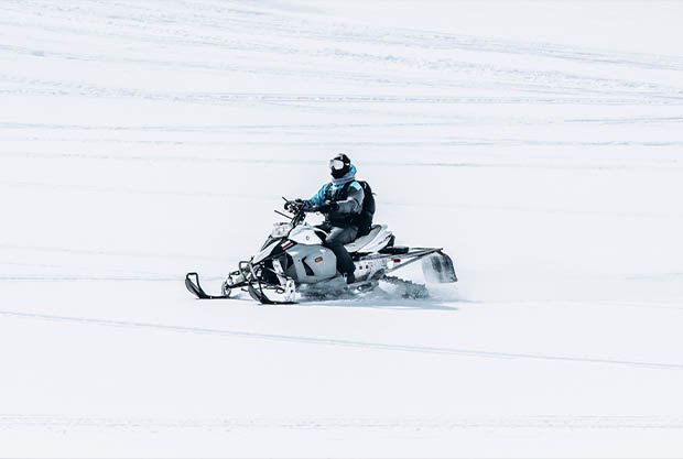 male-riding-snowmobile-large-snowy-field